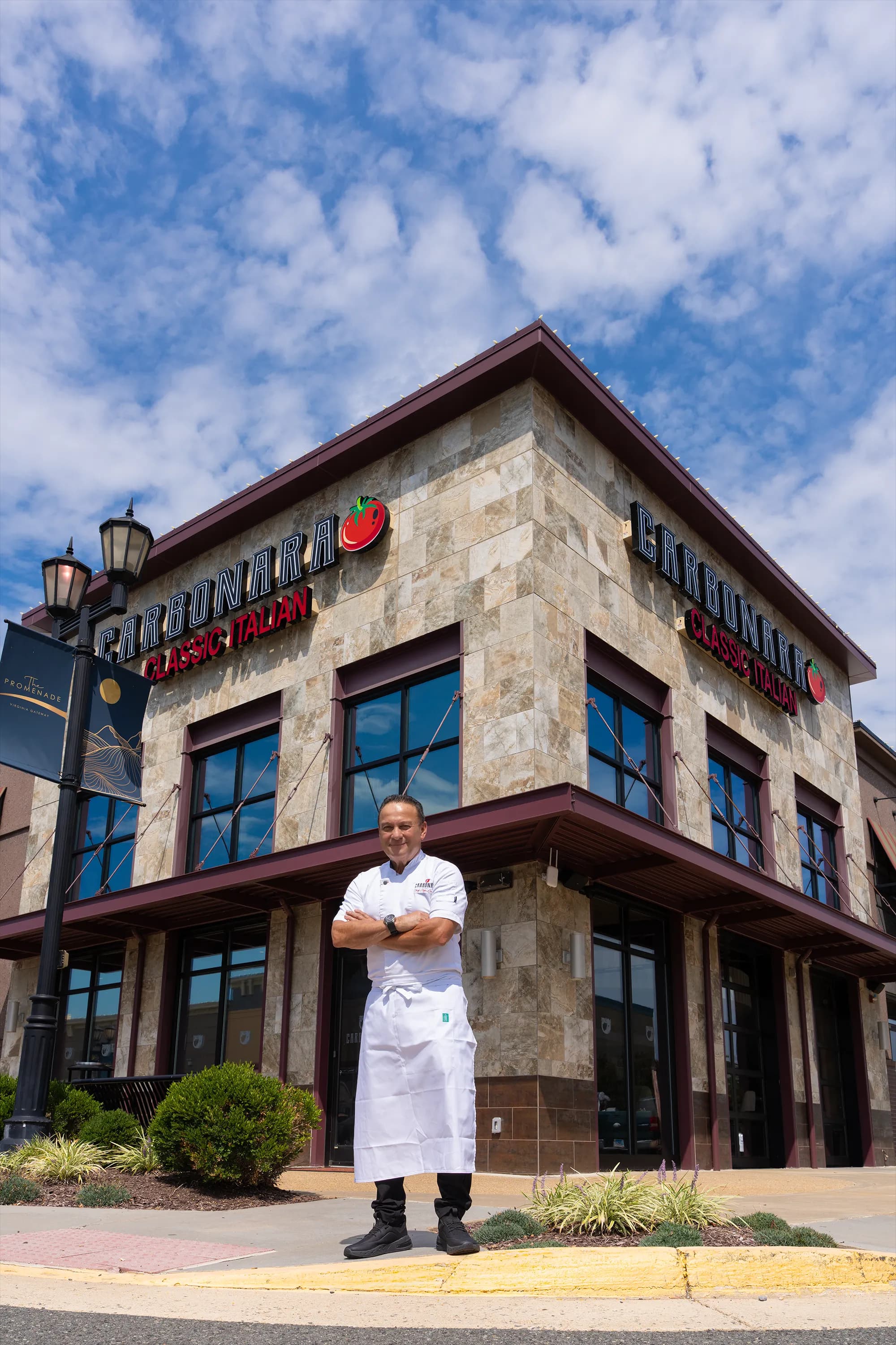 Chef Mike Cordero outside Carbonara Gainesville, in chef's whites beneath the sign